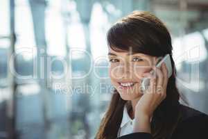 Smiling businesswoman talking on mobile phone at railway station