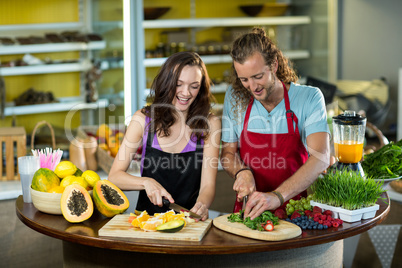 Two shop assistant chopping vegetables and fruits at counter