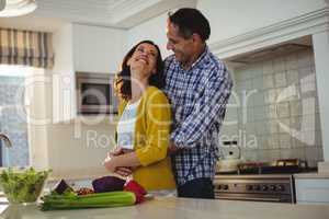Couple embracing each other in kitchen
