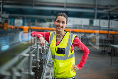Smiling female factory worker standing next to production line
