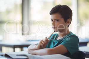 Thoughtful schoolboy studying in classroom