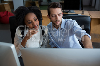 Man and woman discussing over desktop pc