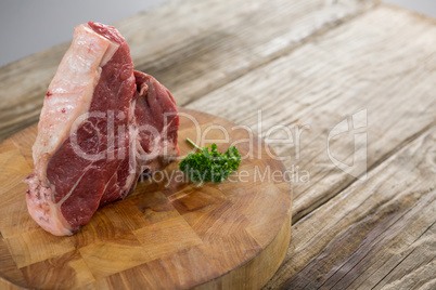 Sirloin chop and corainder leaves on wooden tray against wooden background