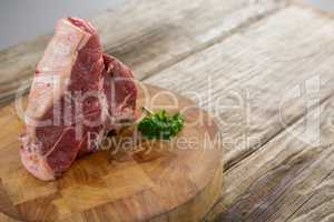 Sirloin chop and corainder leaves on wooden tray against wooden background