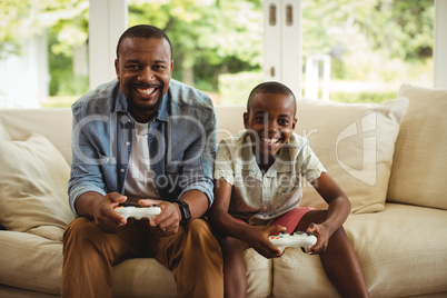 Portrait of father and son playing video game in living room