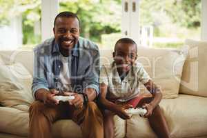 Portrait of father and son playing video game in living room