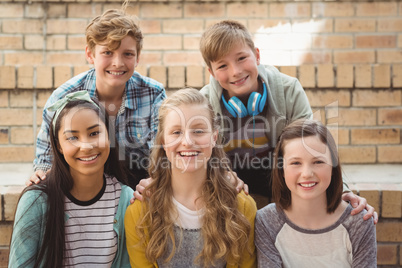 Portrait of smiling school students sitting on the staircase in campus