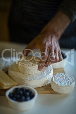 Salesman arranging cheese at counter