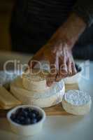 Salesman arranging cheese at counter