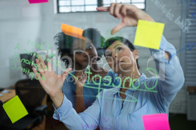 Female graphic designer pointing to the sticky notes on the glass