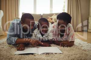 Parents and son reading a book while lying on a rug