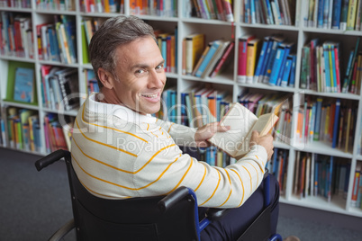 Portrait of disabled school teacher holding book in library