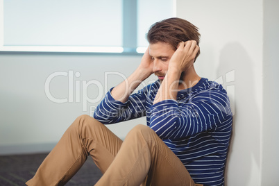 Sad business executive sitting against wall