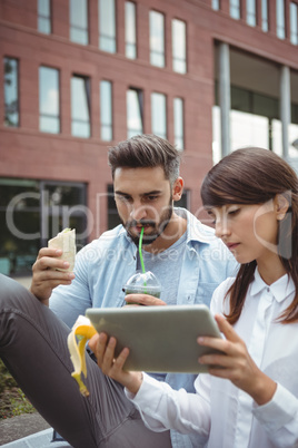 Executives using digital tablet outside building