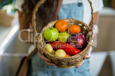 Woman holding a basket of fruits and vegetables in the grocery store