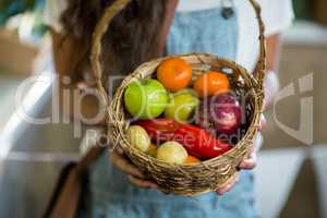 Woman holding a basket of fruits and vegetables in the grocery store