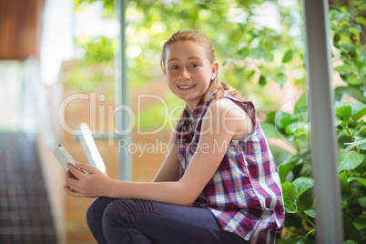 Portrait of happy schoolgirl holding mobile phone