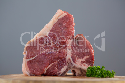 Sirloin chop and corainder leaves on wooden tray