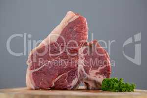 Sirloin chop and corainder leaves on wooden tray