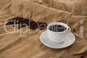 Coffee cup with coffee beans on sack