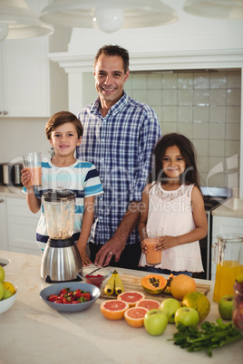 Portrait of father and kids holding glass of smoothie