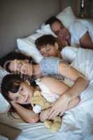 Parents and kids sleeping on bed