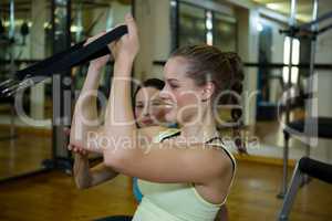 Female trainer assisting woman with stretching exercise