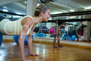Woman doing pilates exercises on fitness ball with coach in fitness studio