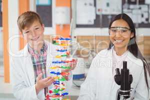 Portrait of happy school kids experimenting molecule model in laboratory