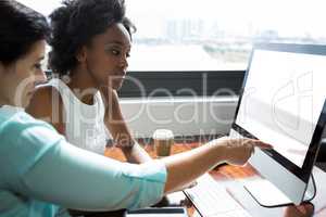 Female graphic designer pointing to desktop pc