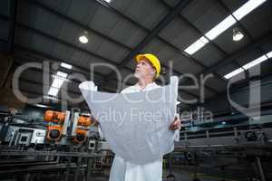 Thoughtful factory engineer holding blueprint