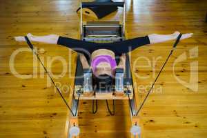 Determined woman practicing stretching exercise on reformer