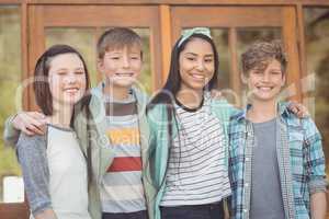 Portrait of happy students standing with arms around in campus