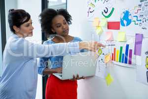 Female graphic designers disussing over a graph on white board