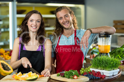 Two shop assistant chopping fruits at the counter in health grocery shop