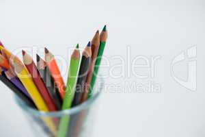 Colored pencils kept in glass on white background