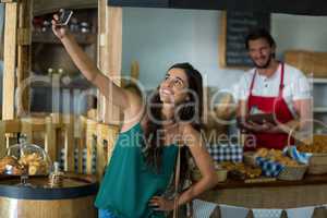 Smiling woman talking selfie with mobile phone at counter
