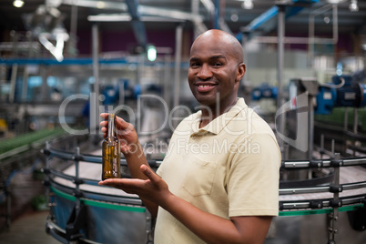 Smiling factory worker holding empty bottle
