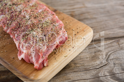 Raw beef ribs on wooden tray against wooden background