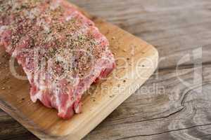 Raw beef ribs on wooden tray against wooden background