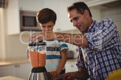 Father and son preparing smoothie in kitchen