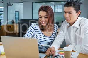 Man and woman working on laptop at desk