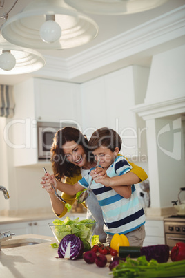 Mother and son mixing the salad in kitchen