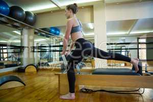 Determined woman performing stretching exercise on reformer