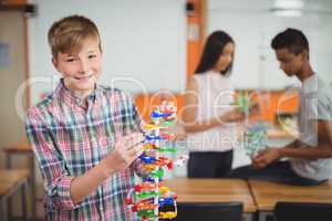 Portrait of smiling schoolboy examining the molecule model in laboratory