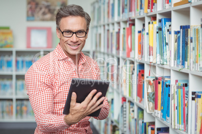 Portrait of happy school teacher using digital tablet in library