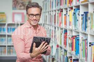 Portrait of happy school teacher using digital tablet in library