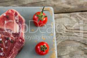Sirloin steak and cherry tomatoes on board against wooden background