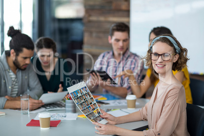 Portrait of smiling graphic designer holding photos in office