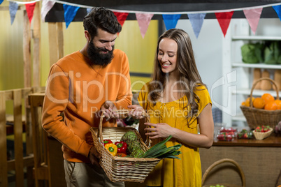 Man and woman holding a basket of vegetables at the grocery store